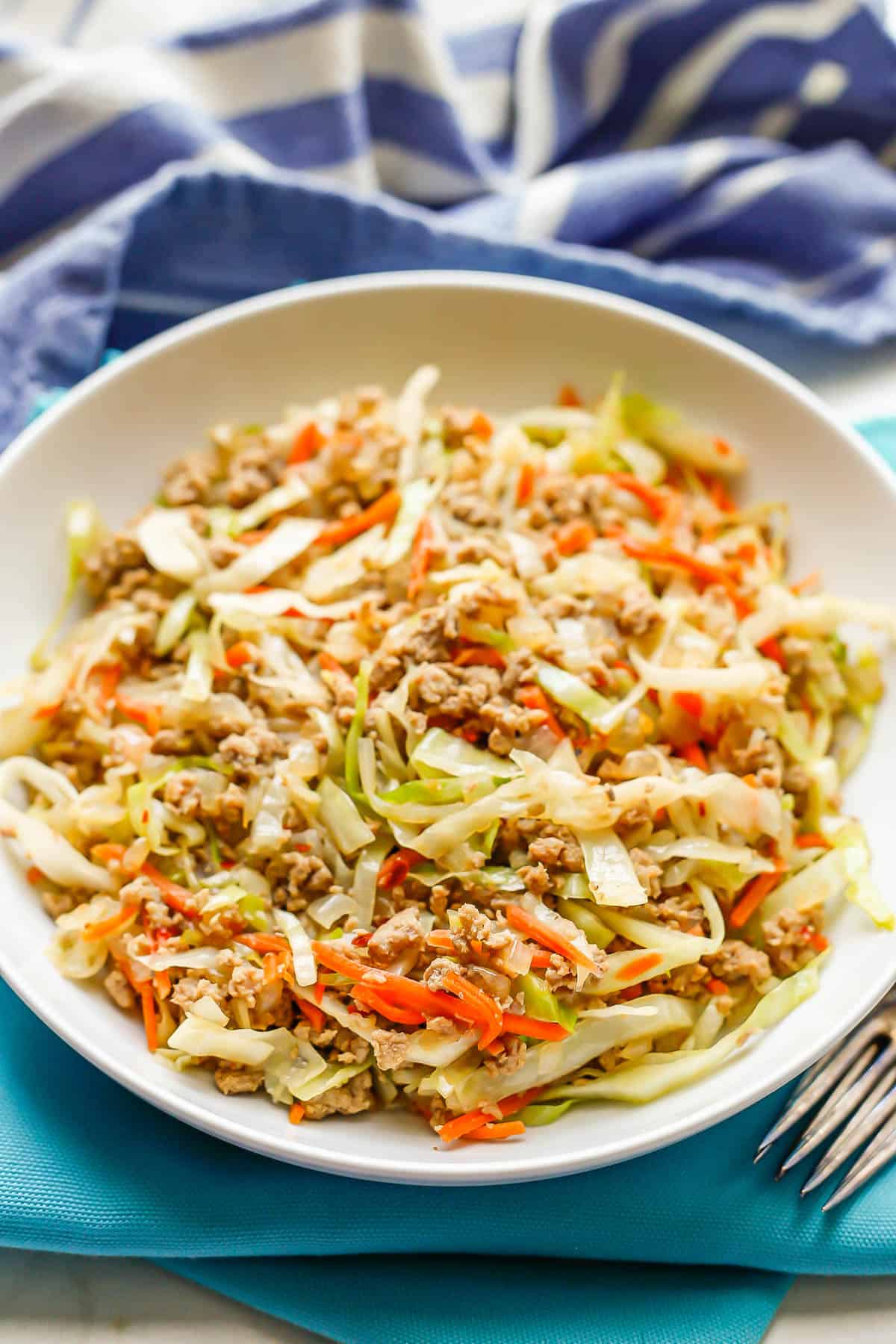 Egg roll in a bowl set on teal napkins with forks resting to the side.