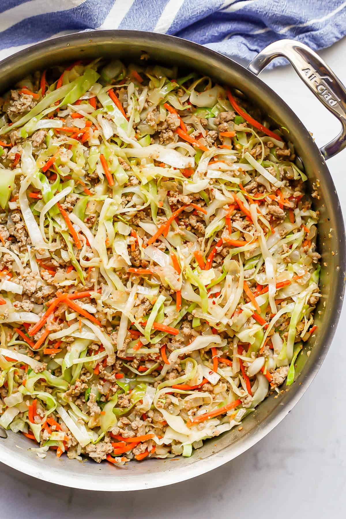 An All Clad skillet with a turkey and cabbage mixture all cooked together.