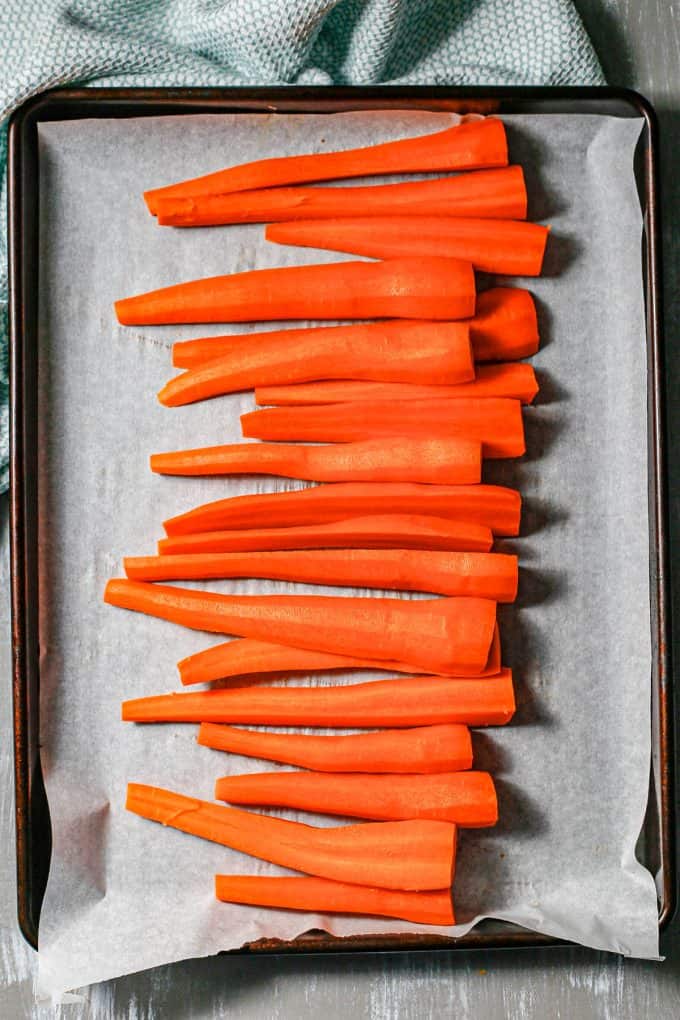 Roasted carrots on a parchment paper lined baking sheet.