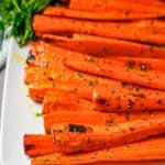 Roasted carrots served on a white rectangular plate with a bunch of parsley as garnish and a text overlay on the photo.