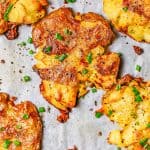 Close up of roasted smashed potatoes on a parchment paper lined baking sheet with a text overlay on the photo.