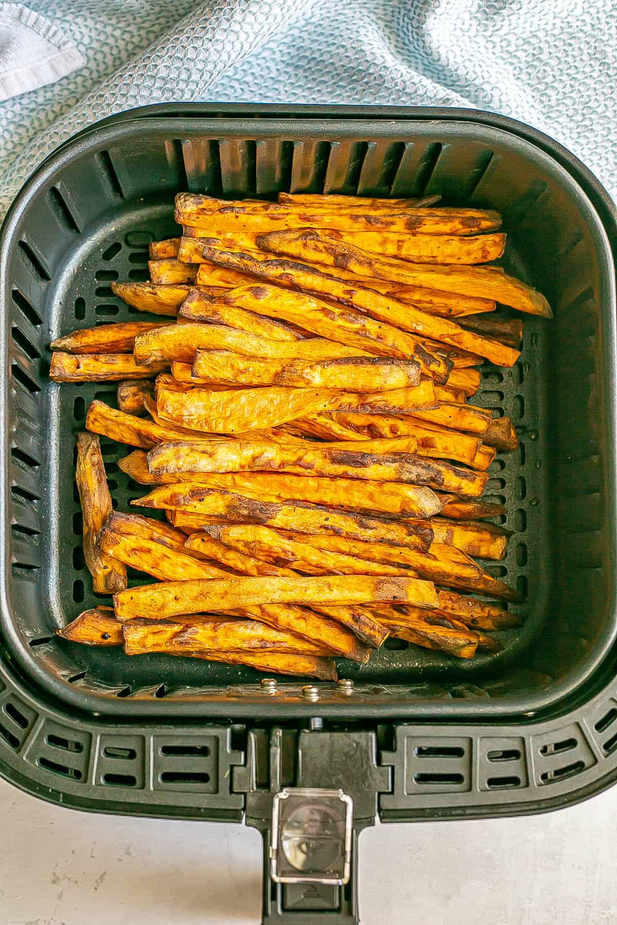 Sweet potato fries stacked up in an Air Fryer after being cooked.