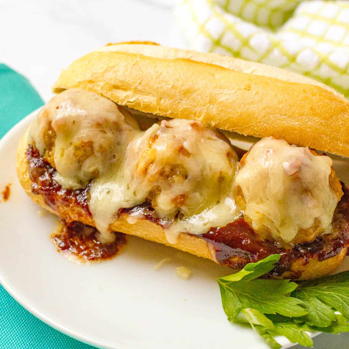 Cheesy chicken meatballs served on a hoagie roll along with some BBQ sauce.
