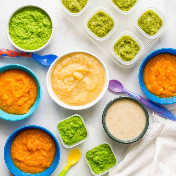 A grouping of small containers of homemade baby food with peas, green beans, applesauce, squash and oatmeal.