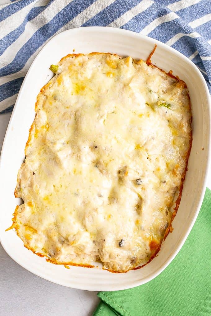 A baked chicken casserole in a rectangular white dish with a layer of melted cheese on top.
