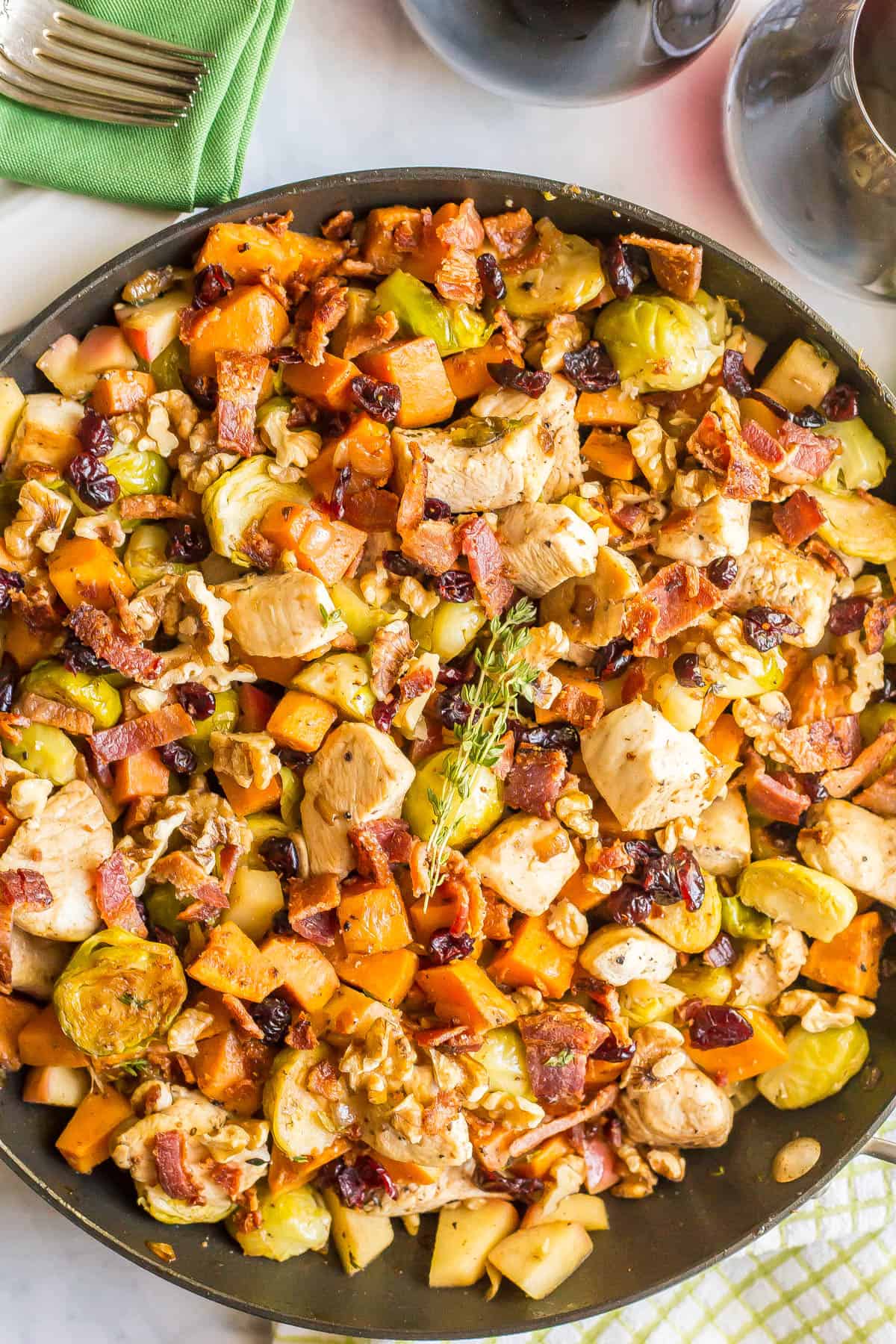 Close up of a one pot harvest chicken skillet topped with a sprig of thyme.