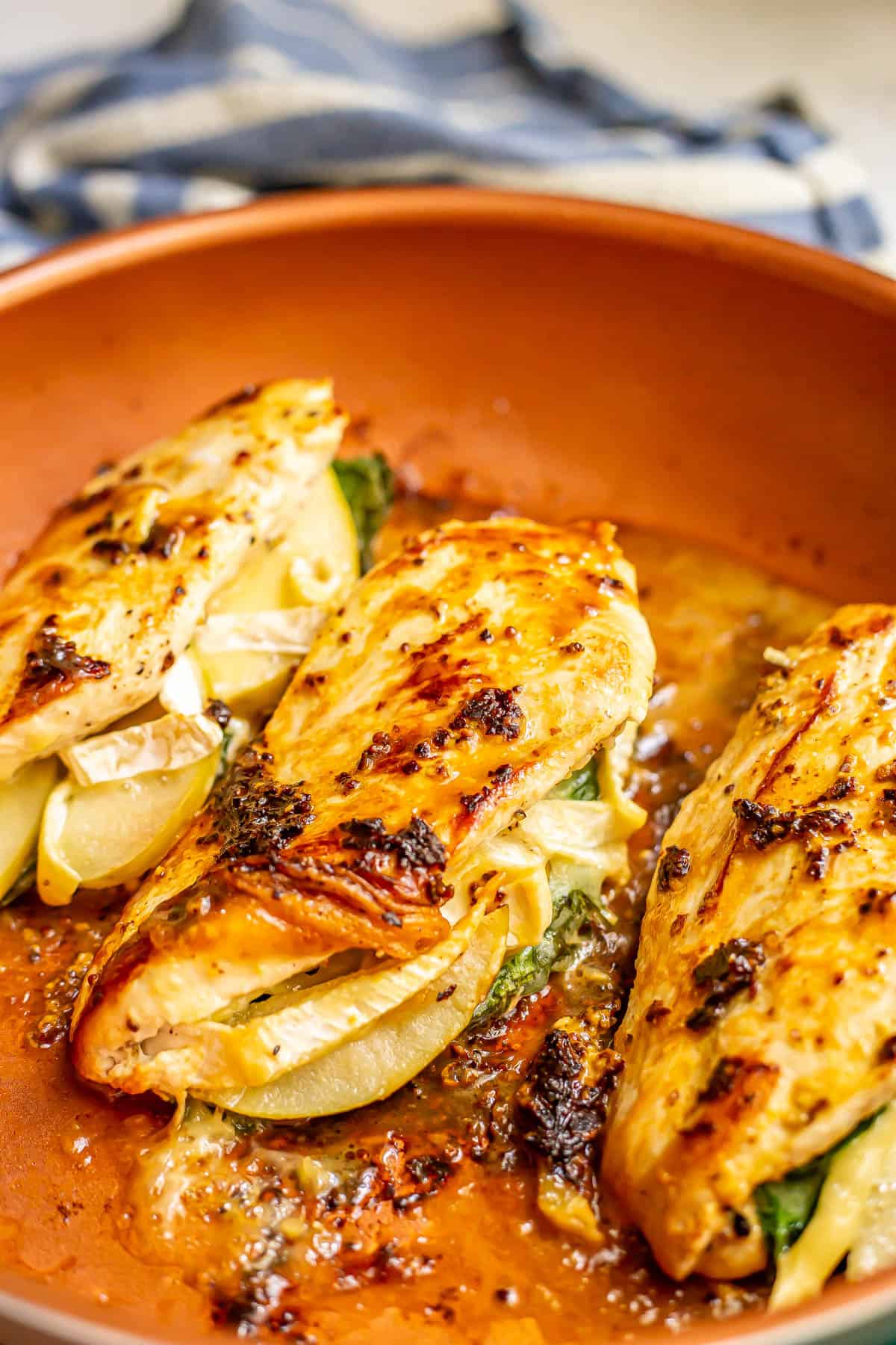 Close up of seared apple brie stuffed chicken breasts in a copper skillet.
