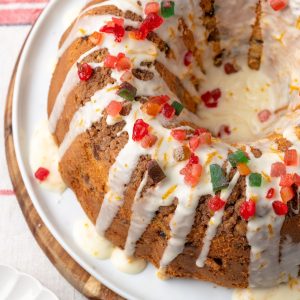 Close up of a Christmas coffee cake with an orange glaze drizzled over top and red and green gummy candies sprinkled on top.