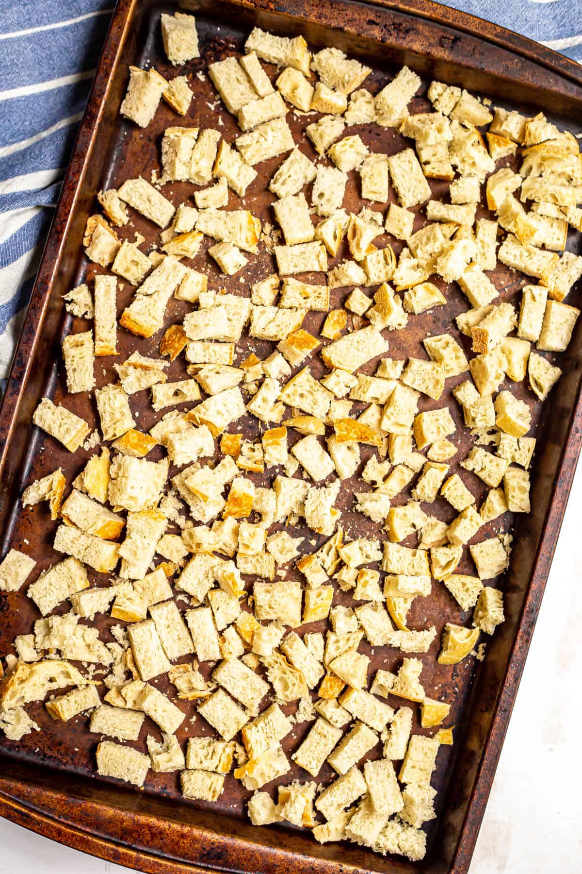 Cubed stale bread cubes on a baking sheet.