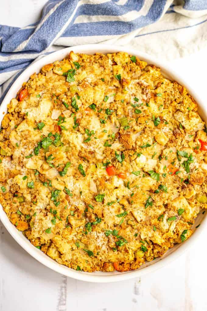 Baked golden brown Thanksgiving dressing in a white round casserole dish.