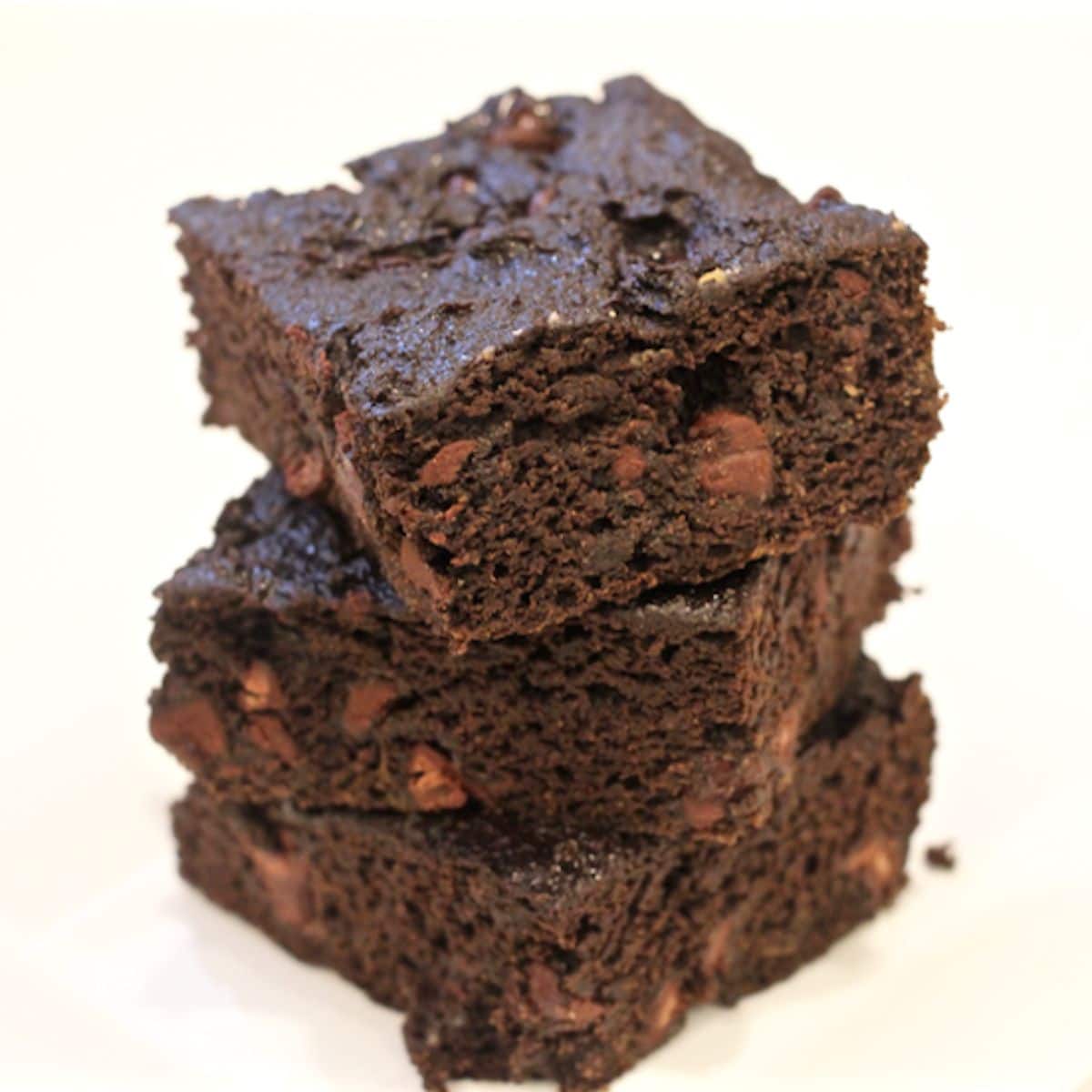 A stack of three pieces of fudgy chocolate pumpkin cake with chocolate chips.