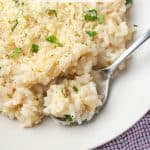 A spoonful of a creamy risotto with Parmesan in a white bowl with a text overlay on the photo.
