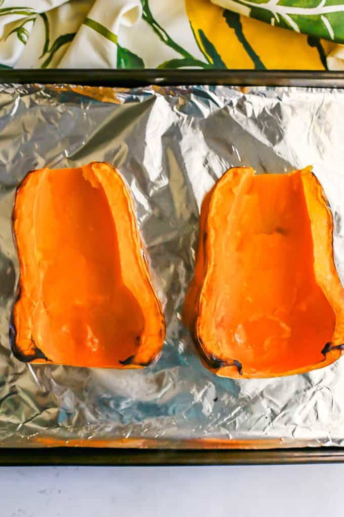 A roasted halved butternut squash on an aluminum foil lined baking sheet.