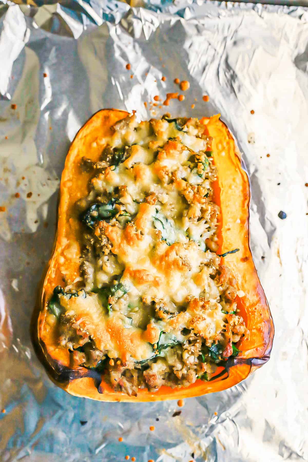 A butternut squash half with a turkey sausage and spinach mixture topped with melted, browned Parmesan cheese.