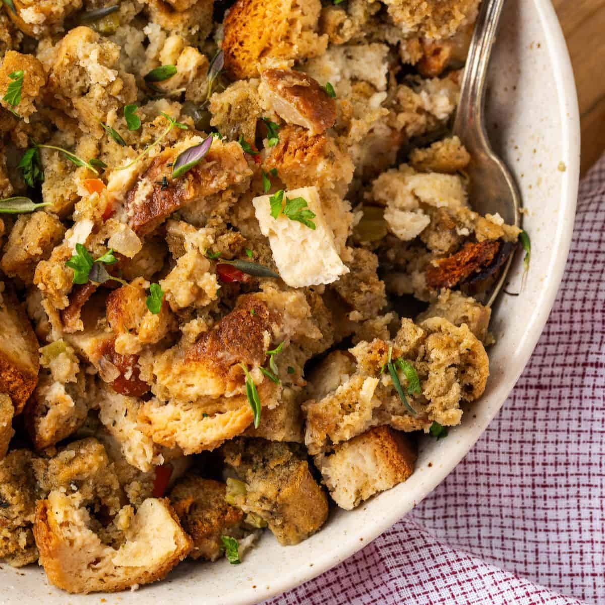 Close up of a spoon resting in a serving dish of Thanksgiving dressing.