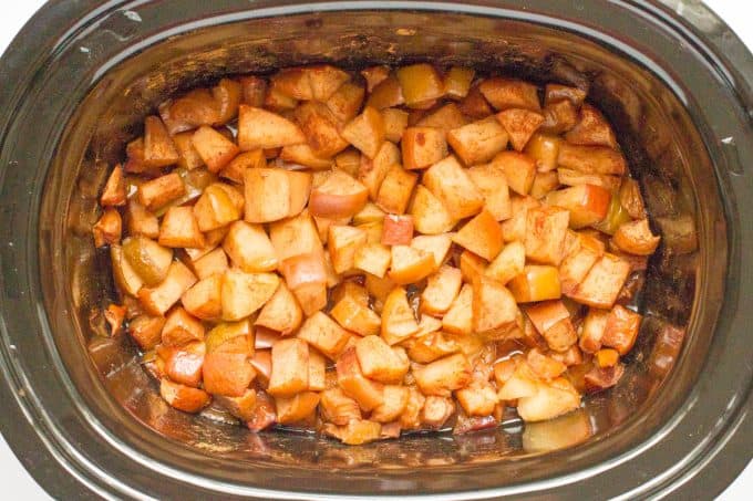 Cooked, softened seasoned apple pieces in a slow cooker.