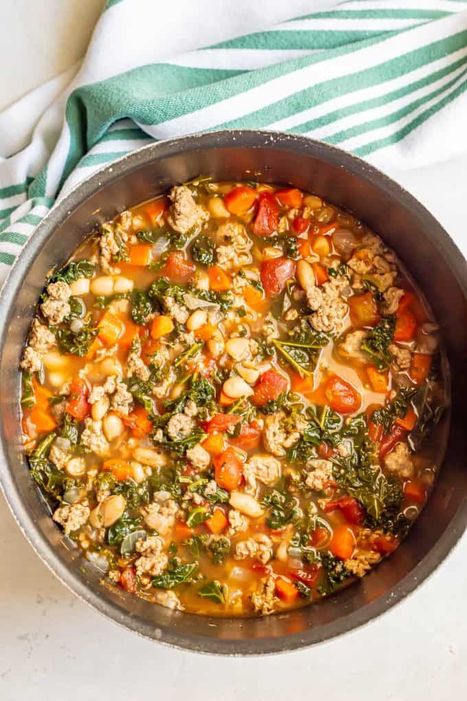 A large pot of soup with ground turkey, tomatoes, carrots and kale.