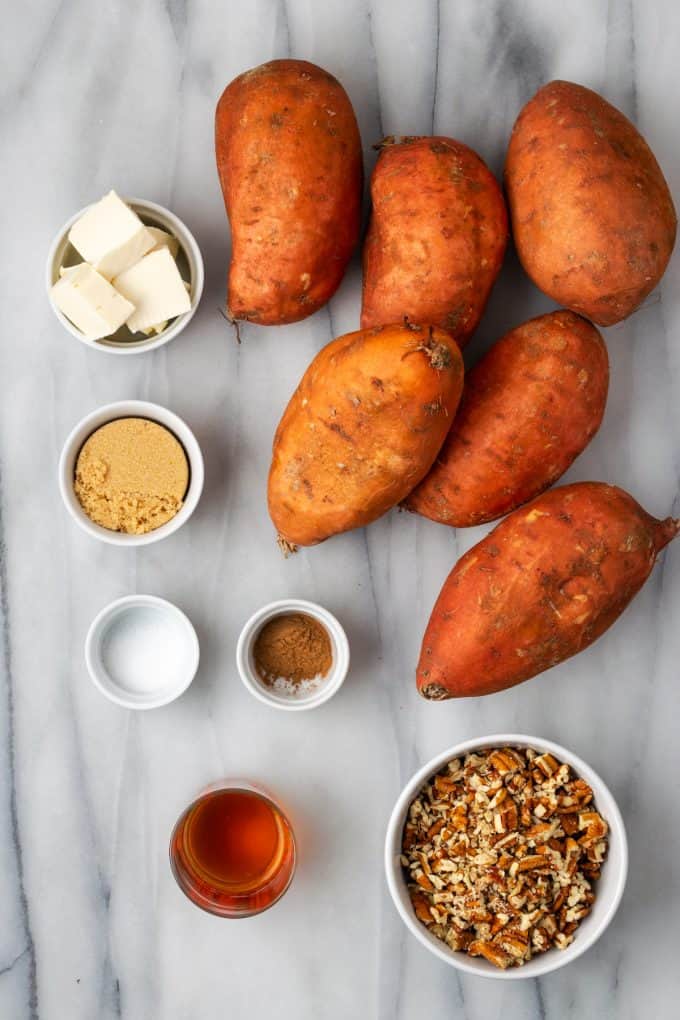 Sweet potatoes and small bowls of ingredients for sweet potatoes laid out on a counter.