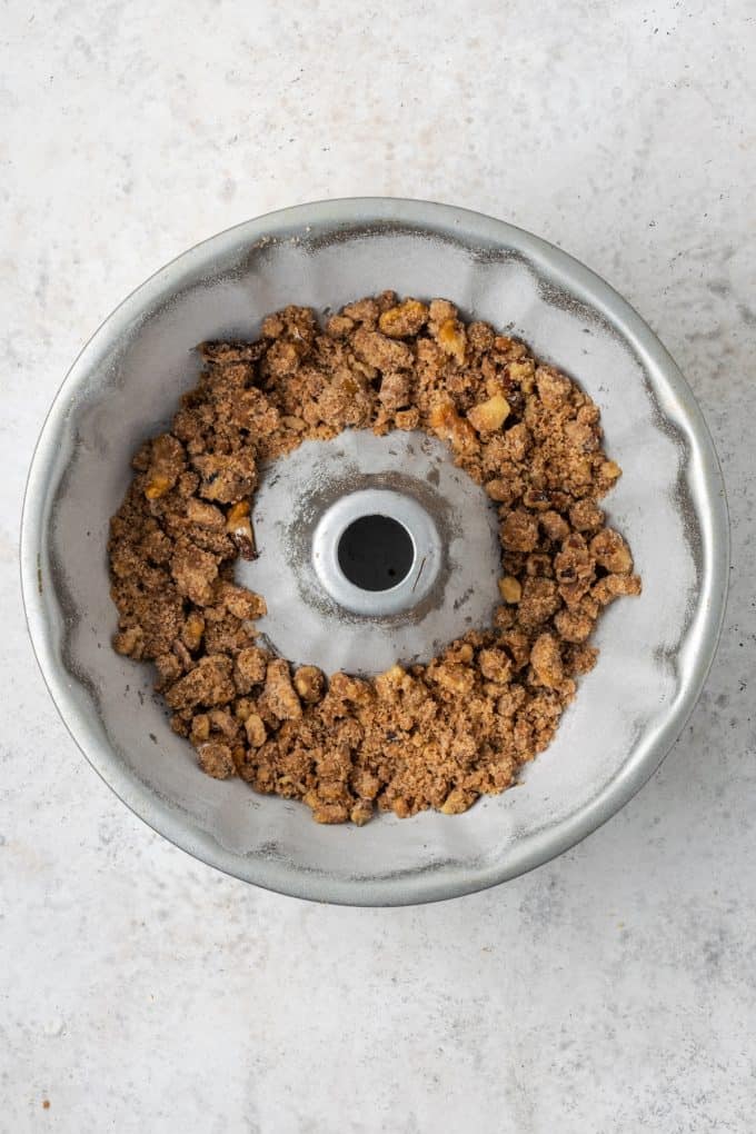 A bundt pan with a layer of streusel in the bottom.