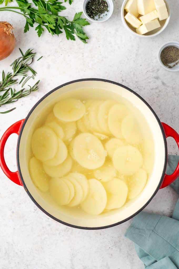 A large stock pot full of sliced potatoes and water.