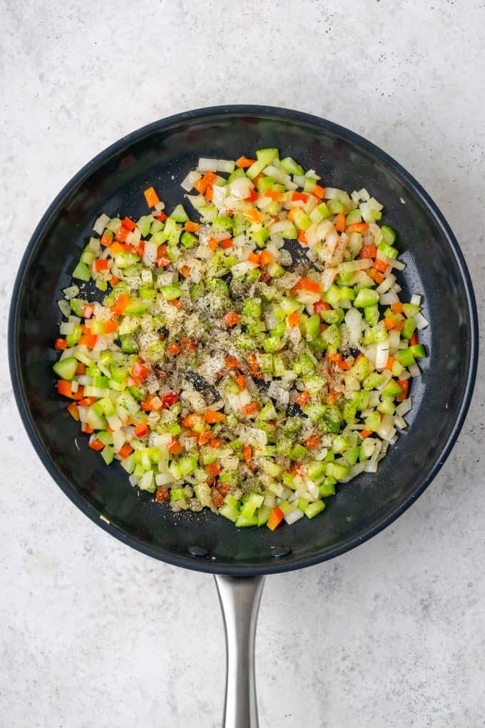 Sautéed onion, celery and red pepper with seasonings in a skillet.