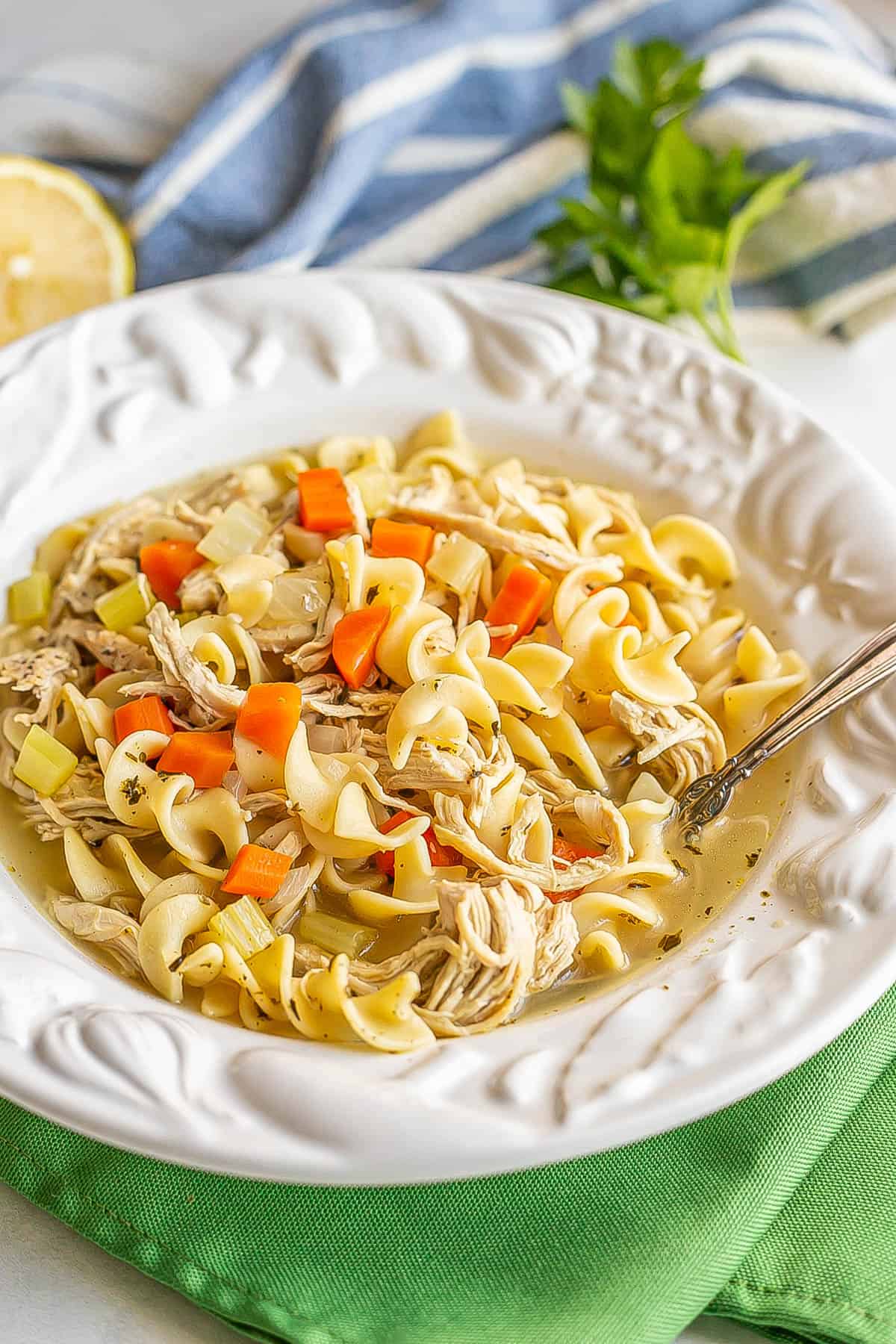 A bowl full of chicken noodle soup set on green napkins.