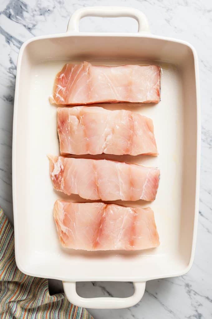 Four pieces of grouper filet placed in a large casserole dish.