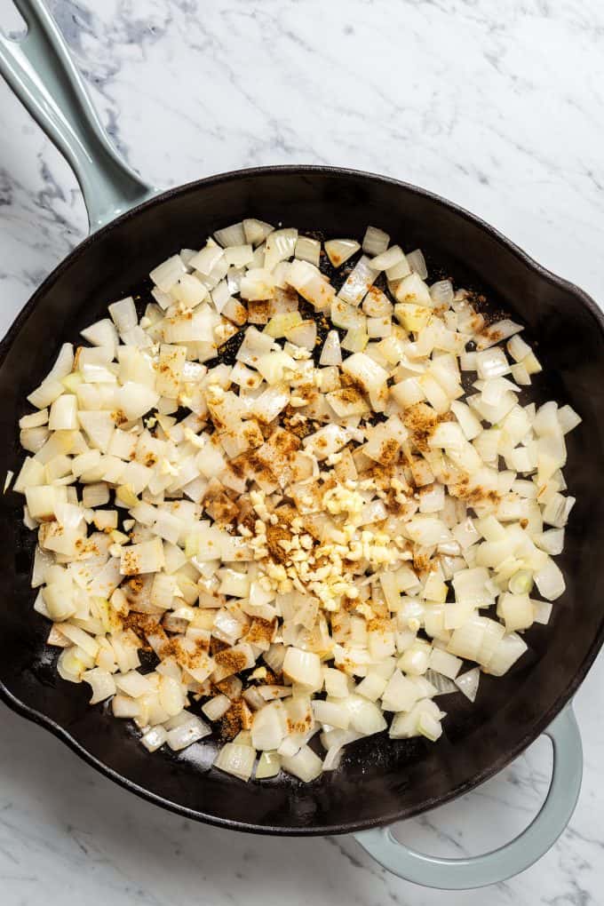 Sautéed onion and garlic with seasonings in a skillet.