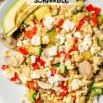 Close up of a white plate with a scrambled egg vegetable mixture with feta cheese on top and avocado slices to the side with a text overlay on the photo.