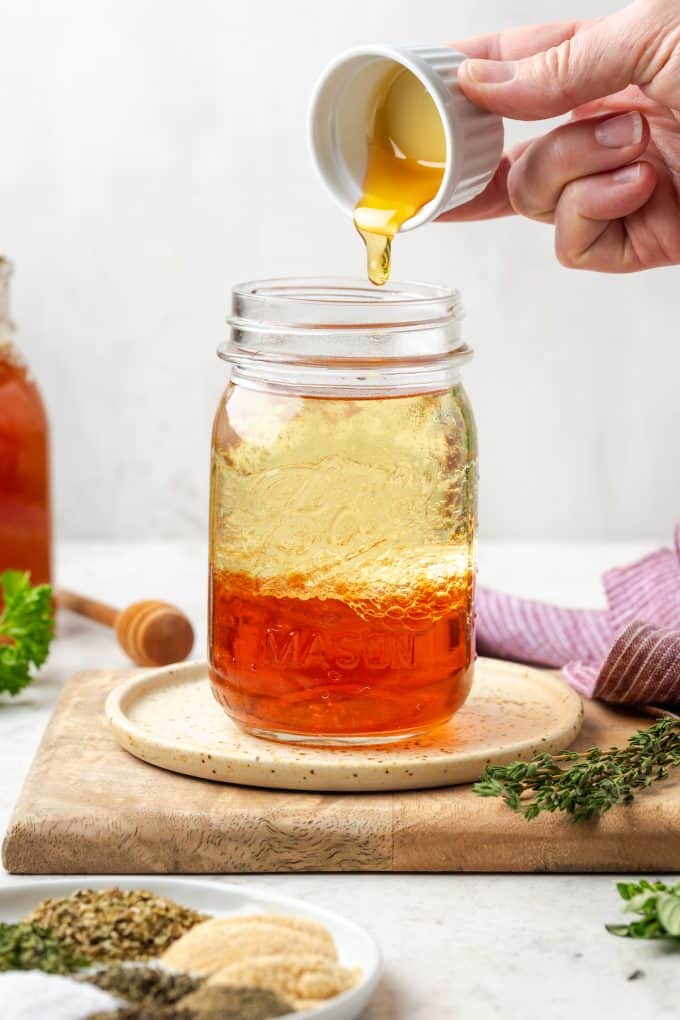 Honey being added to a glass jar.