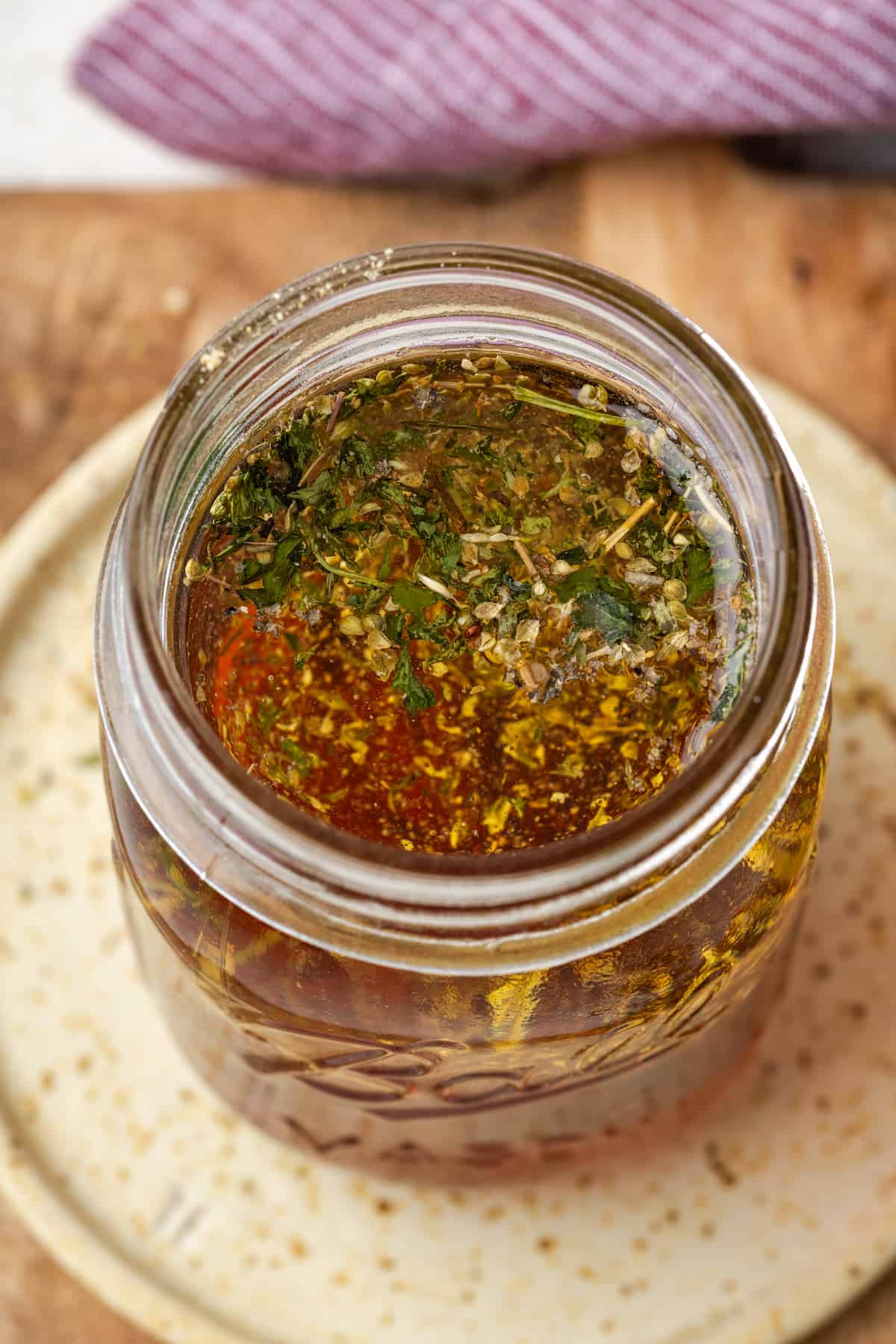 A homemade salad dressing being mixed together in a large glass jar.