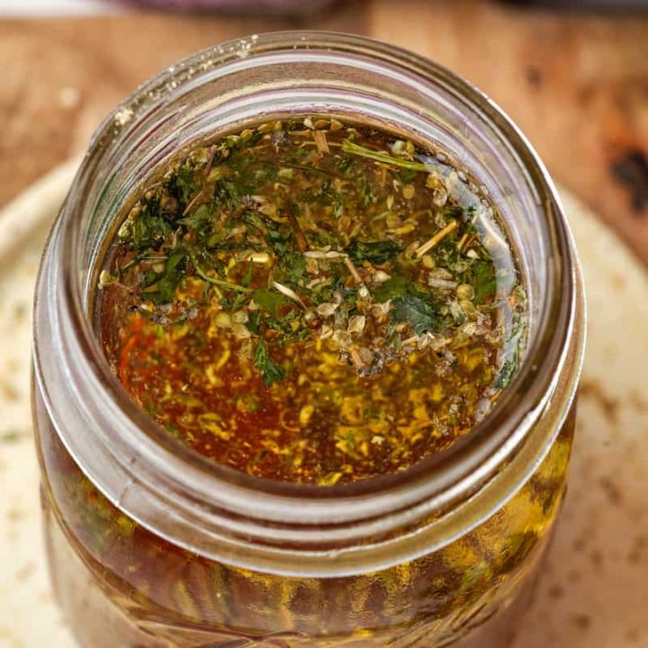 Close up of a homemade dressing with Italian seasonings in a glass jar.