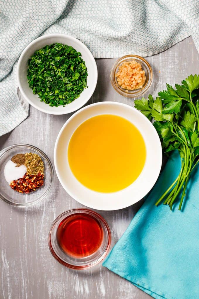 Ingredients laid out in separate bowls for making a chimichurri sauce recipe.