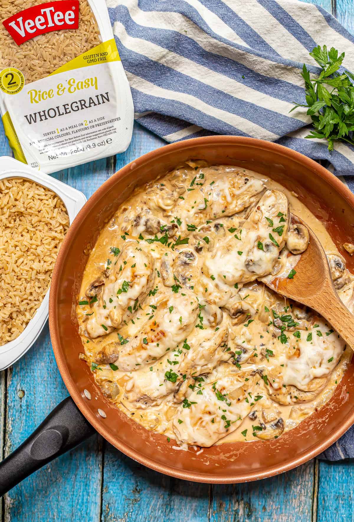 A copper pan of cream cheese chicken strips in a saucy mixture alongside some quick cook rice.