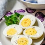 Two hard boiled eggs cut in half and served on a small plate with salt and pepper sprinkled on top and parsley to the side for garnish and a text overlay on the photo.