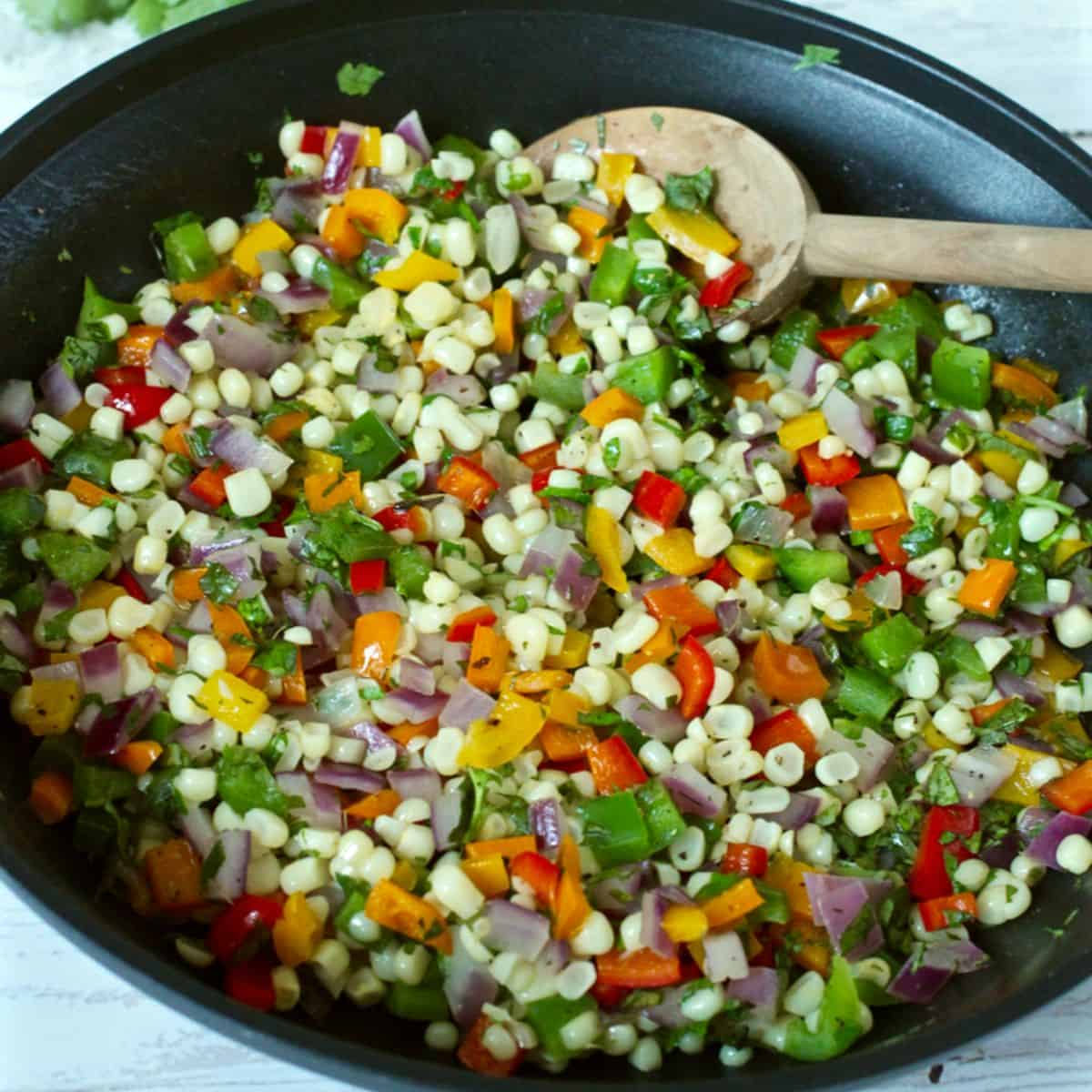 Close up of a colorful skillet mixture of sautéed corn and bell peppers.