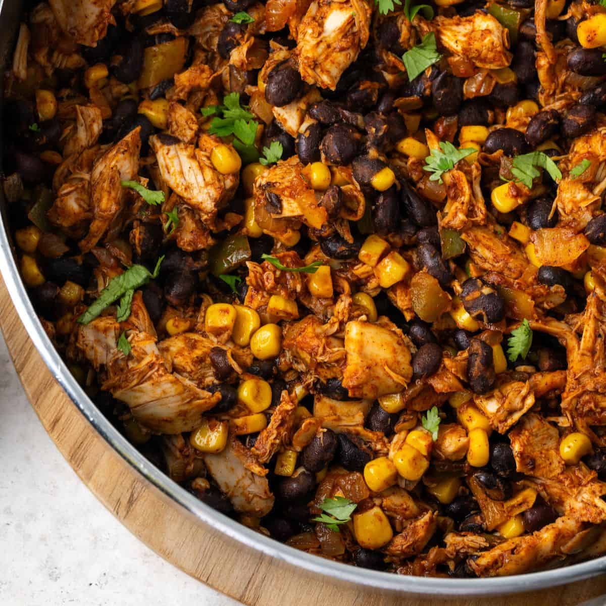 Close up of a southwest chicken skillet with black beans and corn in a large pan with cilantro on top.