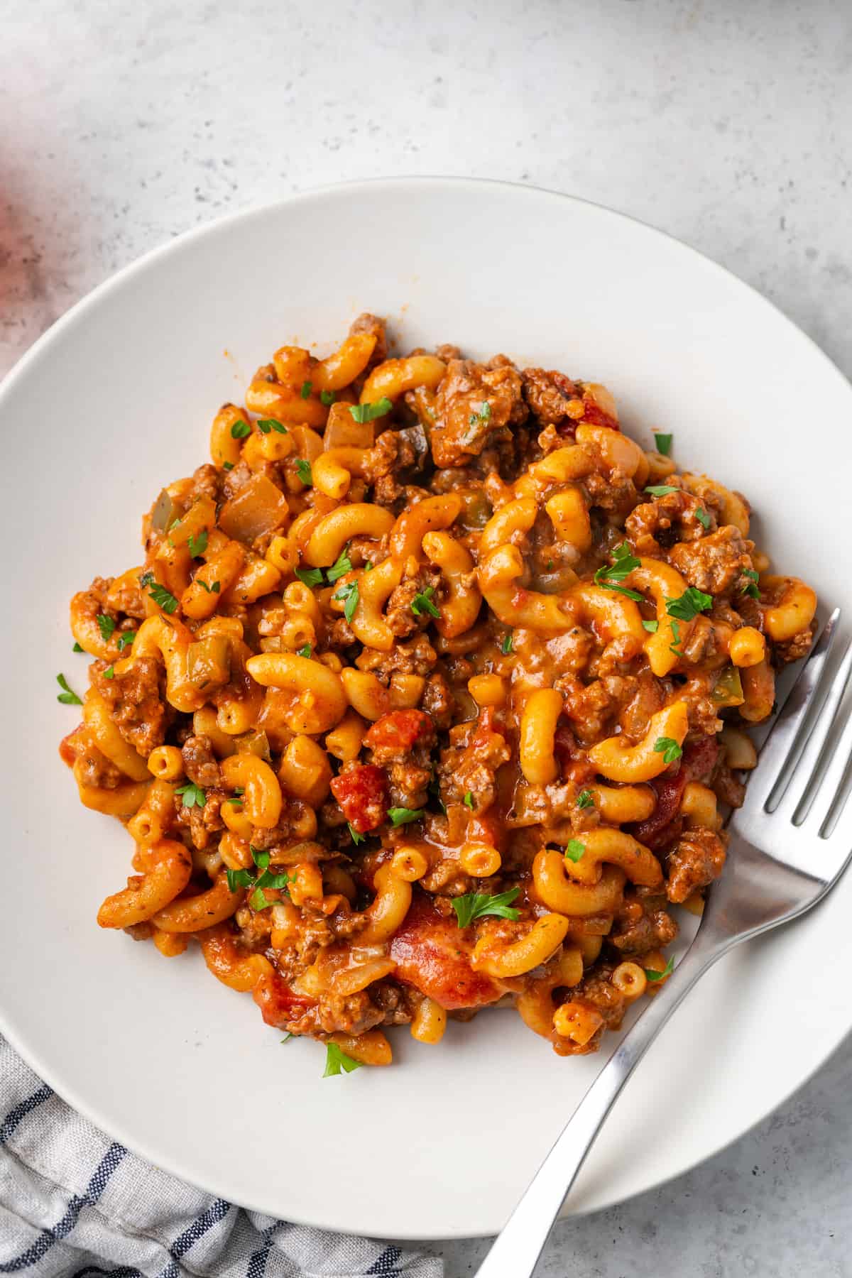 A white plate with American style goulash and a fork to the side.