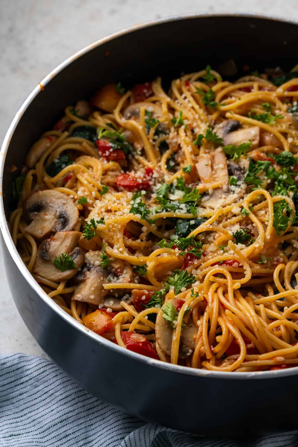 Vegetarian spaghetti with mushrooms, spinach and tomatoes all cooked in a large skillet and topped with parsley and Parmesan cheese.