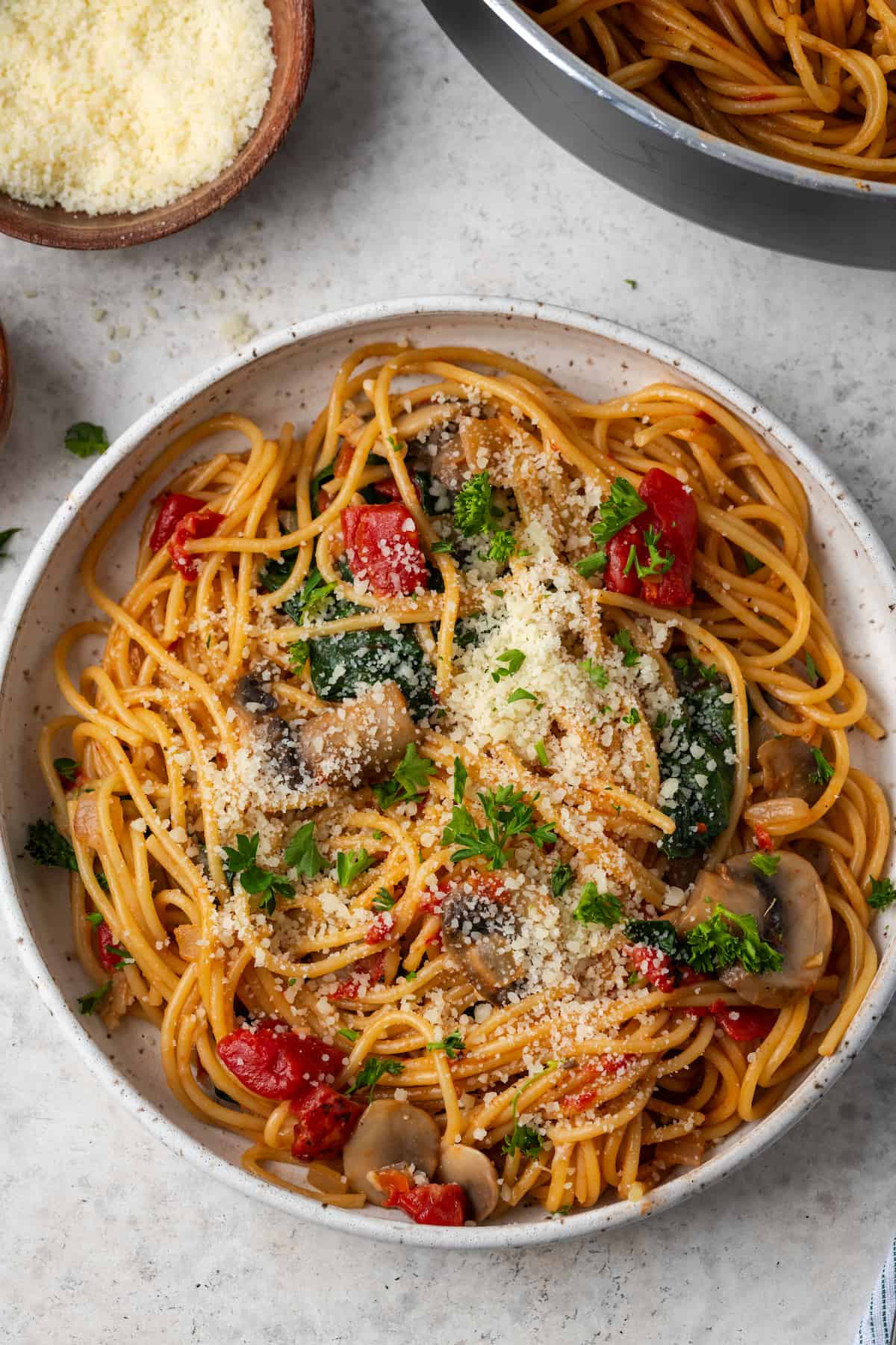 Vegetarian spaghetti served in a low bowl with parsley and Parmesan on top.