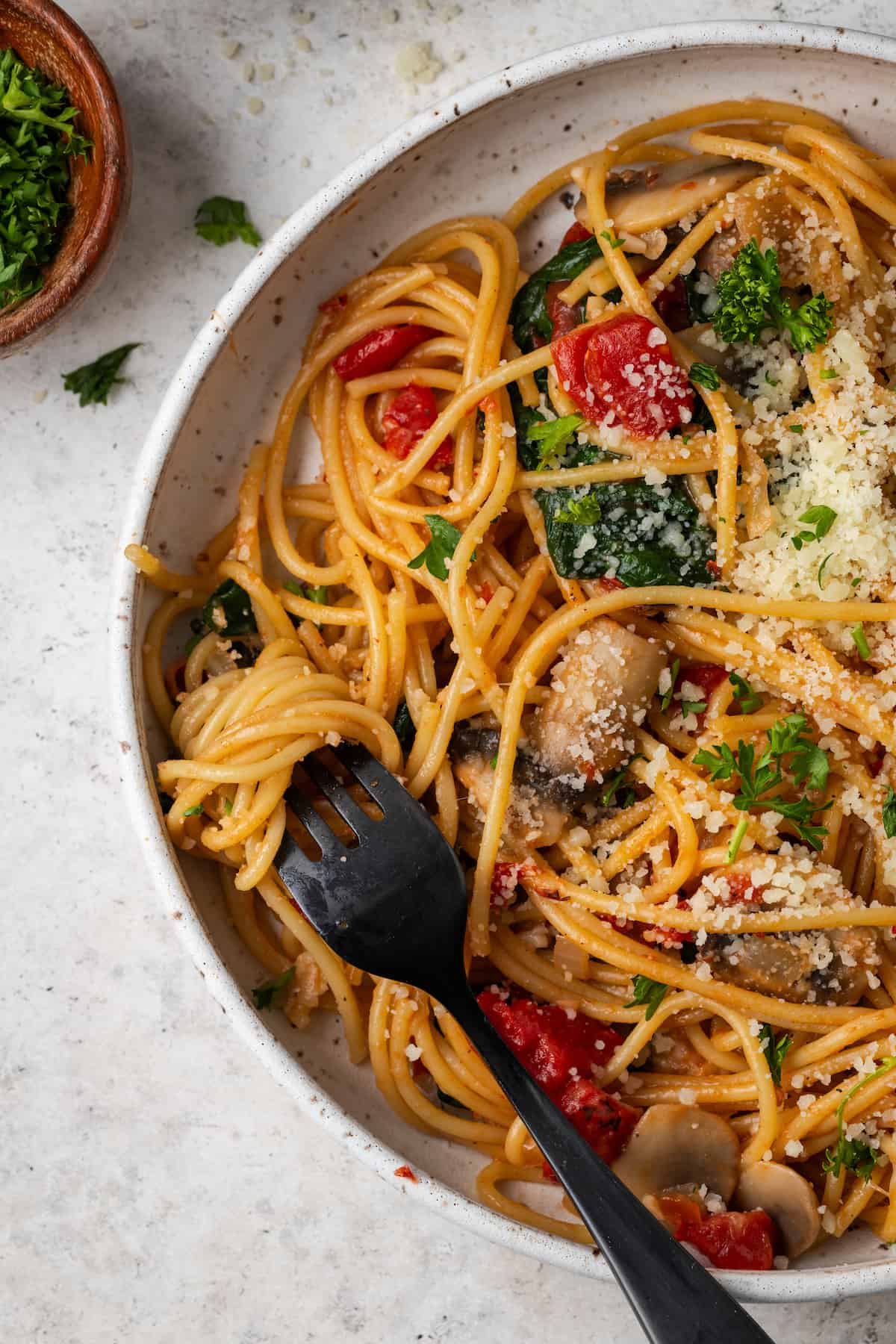 A fork twirling up a bite of vegetarian spaghetti from a low bowl.