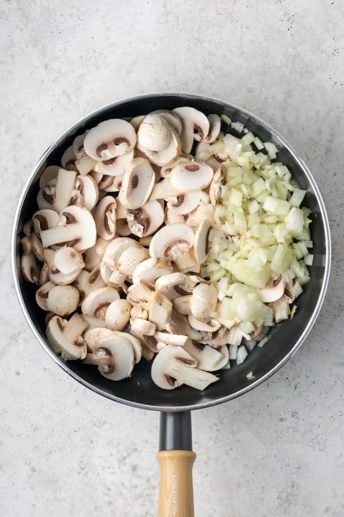 A skillet with onions and sliced mushrooms.