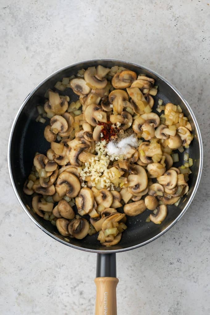 Sautéed onions and mushrooms in a skillet with seasonings added on top.