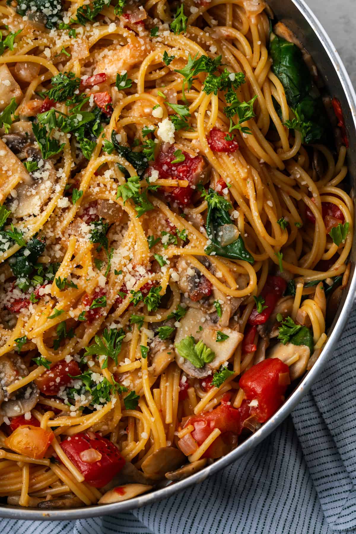 Vegetarian spaghetti with mushrooms, spinach and tomatoes all cooked in a large skillet.