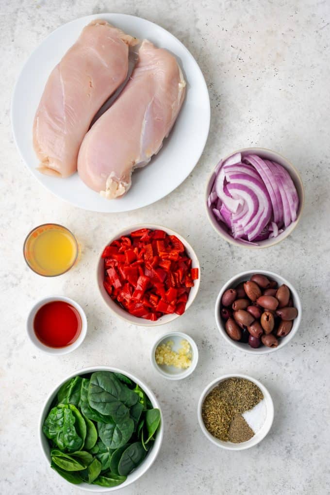 Ingredients laid out in separate bowls for a Greek chicken recipe.