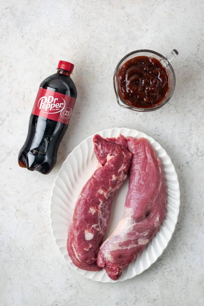 Pork tenderloin, Dr Pepper and BBQ sauce laid out on a counter for making slow cooker pulled pork.