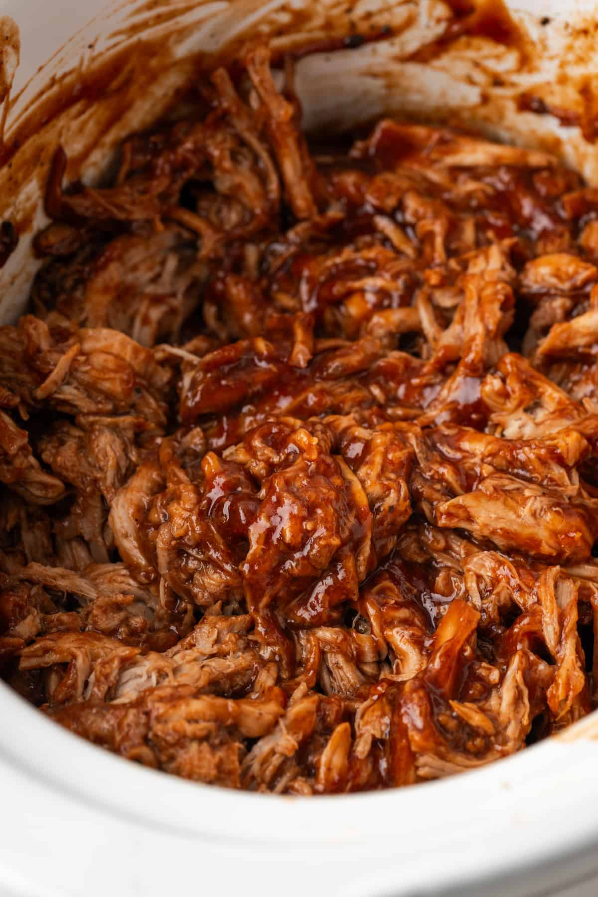 Saucy slow cooker pulled pork in a crock pot insert.