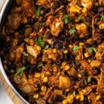 A southwest chicken skillet with black beans and corn in a large pan with a text overlay on the photo.