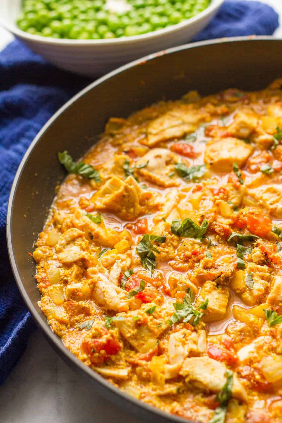Close up of a skillet of chicken and tomatoes in a curry sauce.