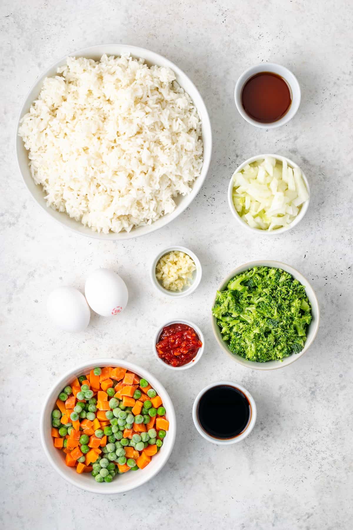 Ingredients laid out in separate bowls for making vegetable fried rice.